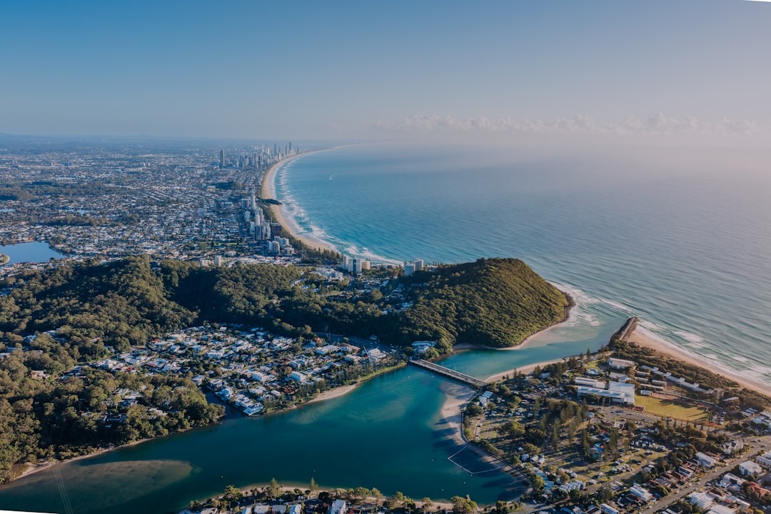 Coastal city with ocean, river, and green hills.